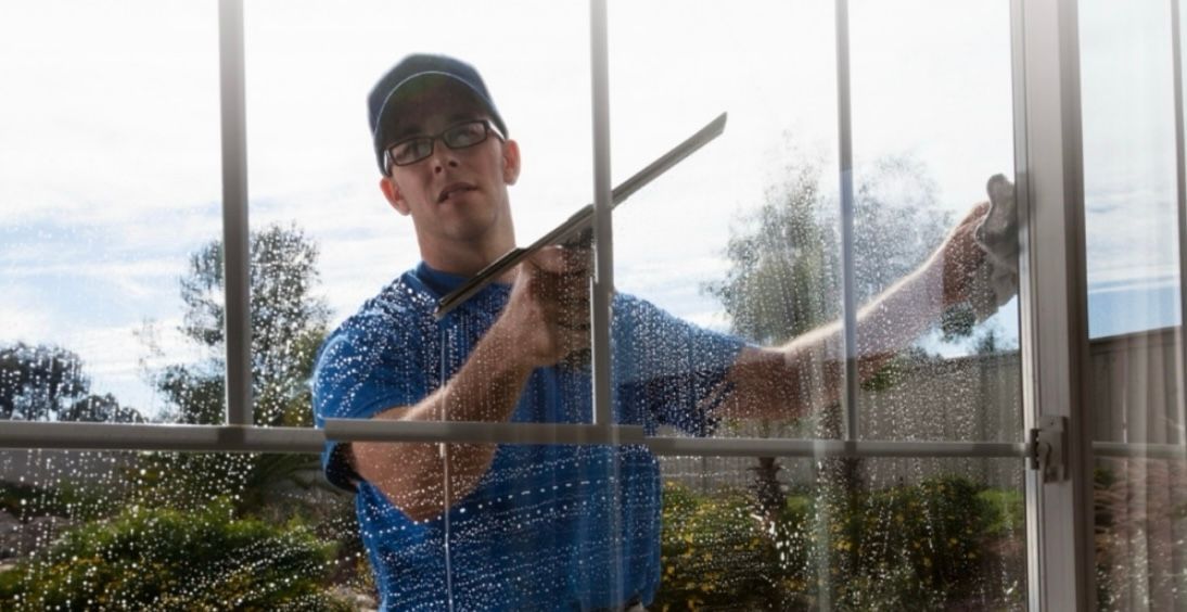 A man is cleaning a window with a squeegee.