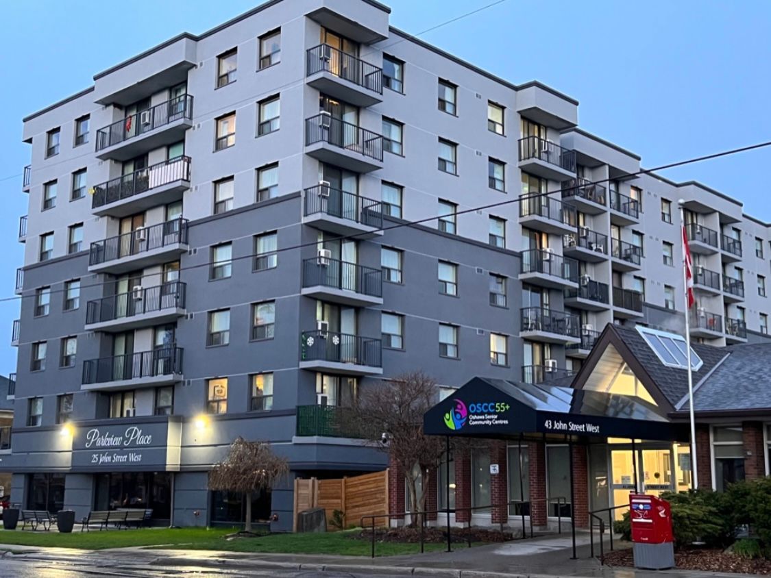 A large apartment building with a bus stop in front of it.