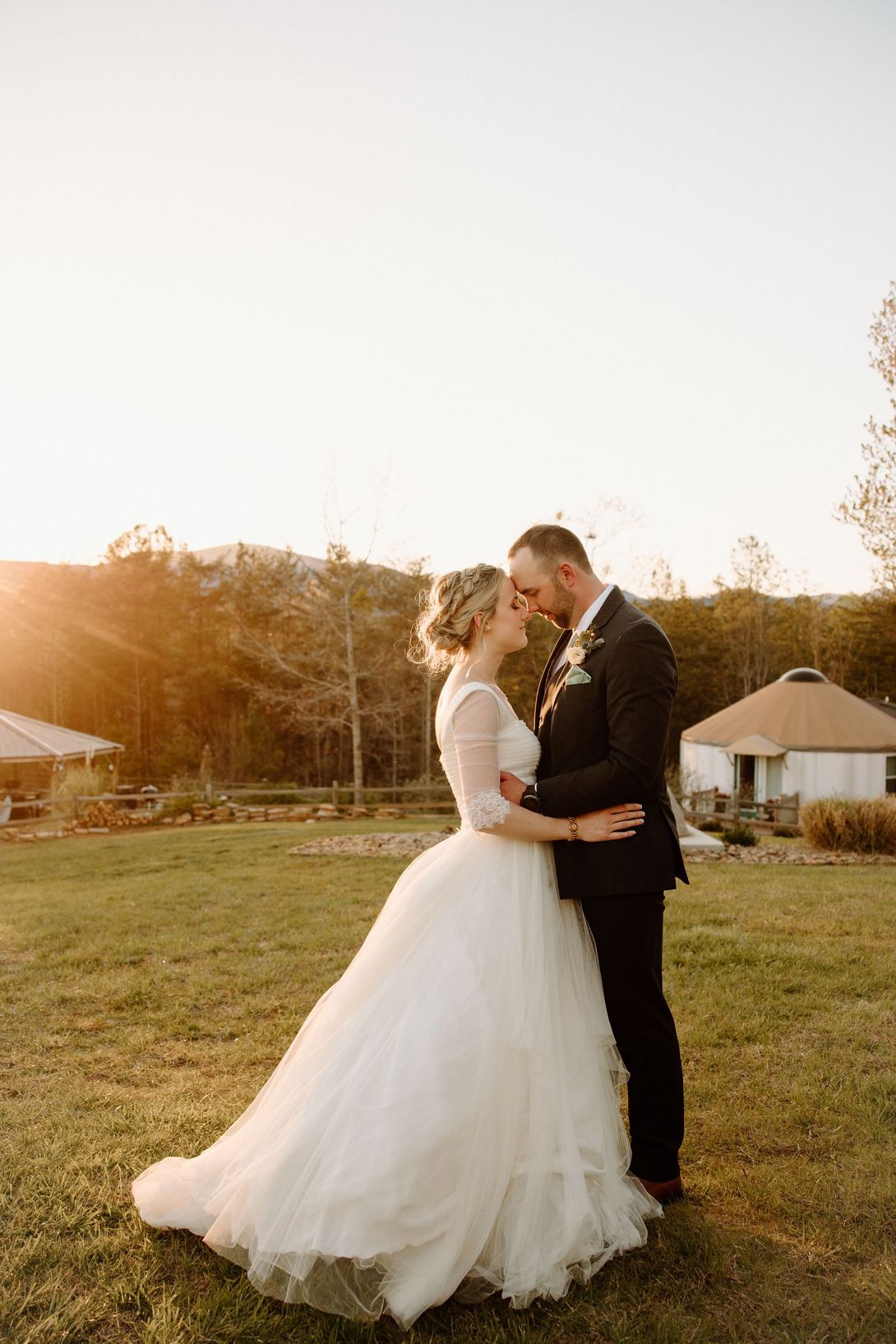 Bride and groom with foreheads touching beside glamping yurt at Serenity Ridge, golden hour in the Blue Ridge Mountains.