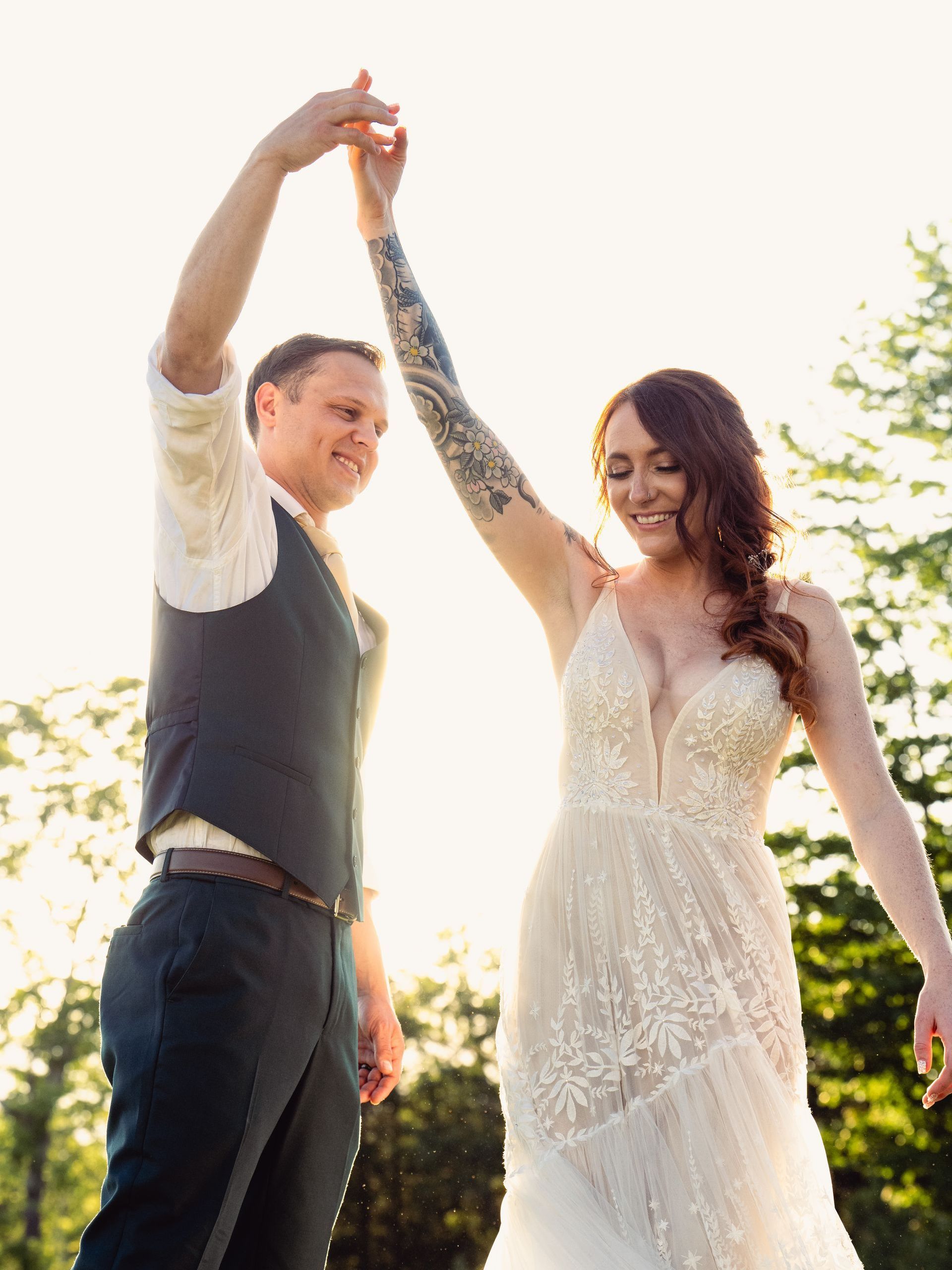 Couple dancing bathed in warm golden hour sunlight at Serenity Ridge, surrounded by mountain views and heartfelt joy.
