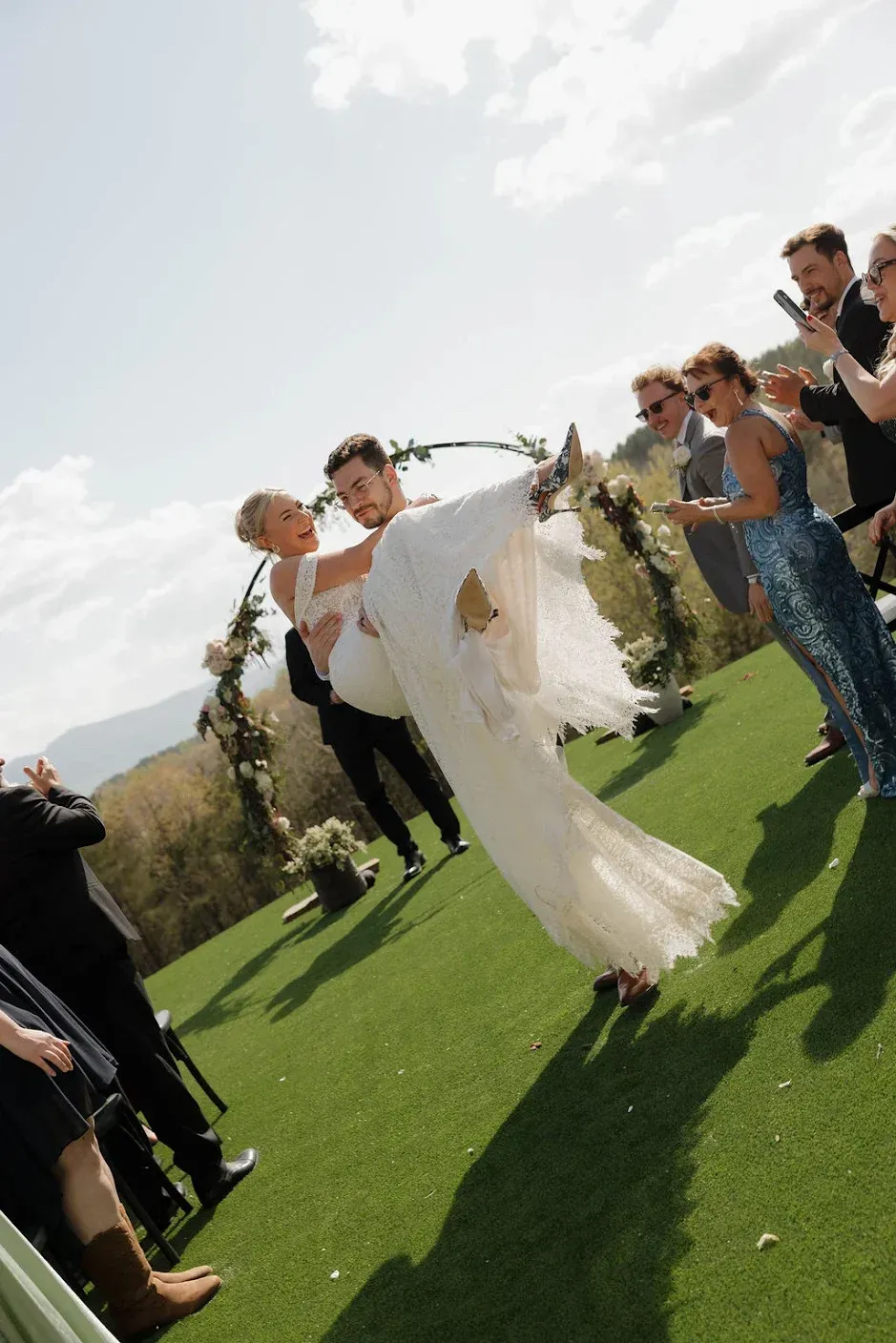 Groom carrying bride as they walk down the aisle after saying “I do” at Serenity Ridge surrounded by mountain beauty in WNC
