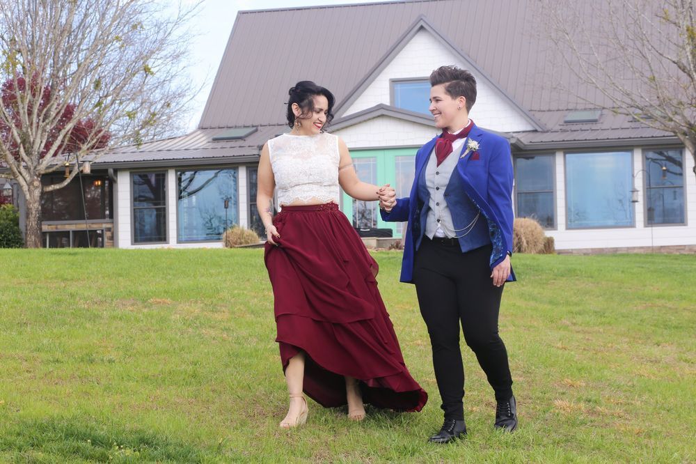 LGBTQ-friendly wedding venue: couple walking hand in hand with Hilltop House and Blue Ridge Mountain at Serenity Ridge.