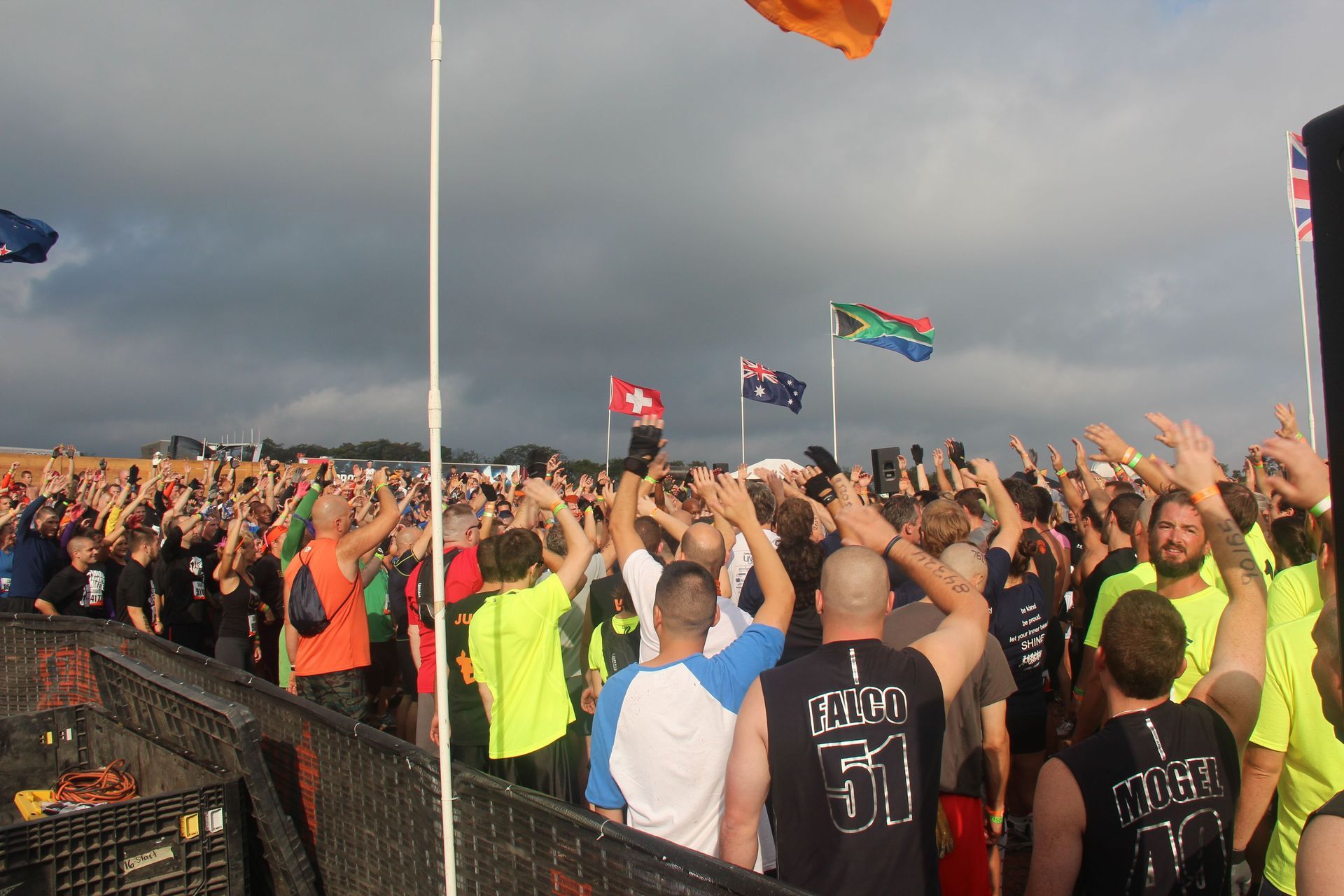 A crowd of people raising their arms in the air with flags in the background