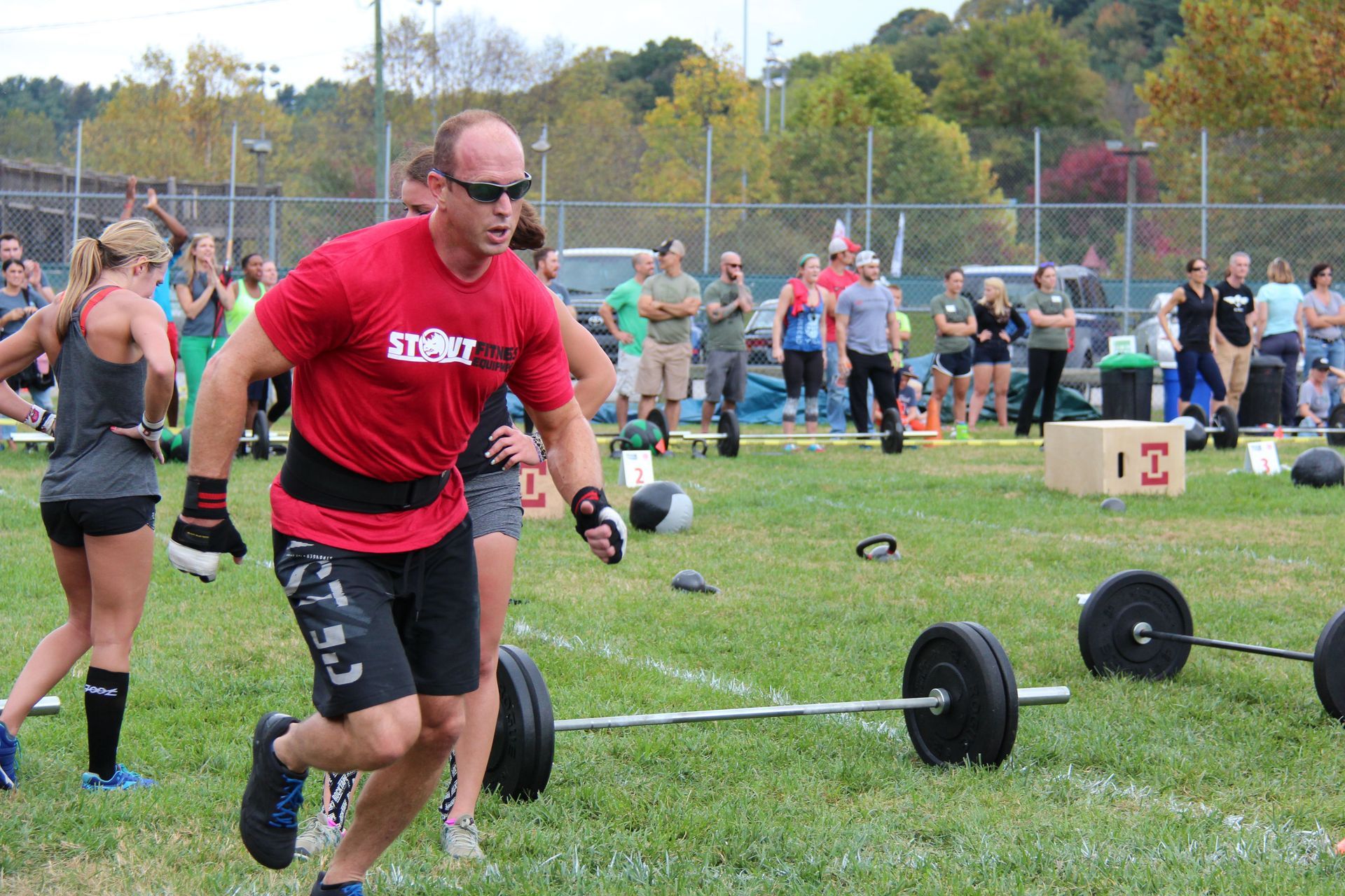 A man in a red shirt is running with a barbell in a field