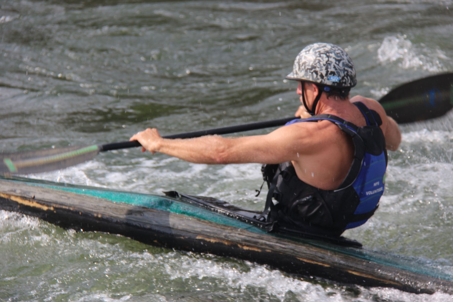 A man is paddling a kayak down a river
