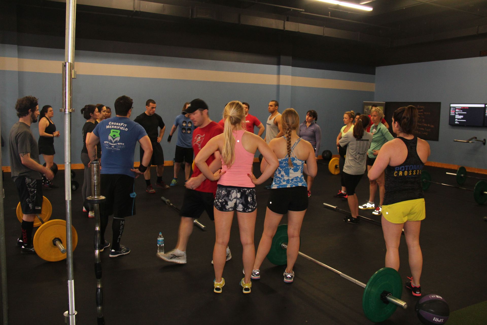 A group of people are standing around a barbell in a gym