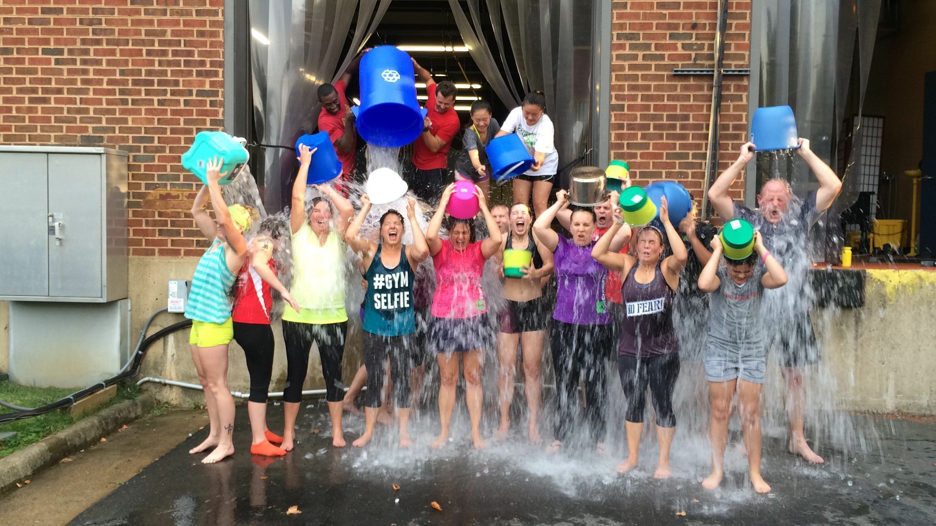 A group of people are standing in front of a building holding buckets of water