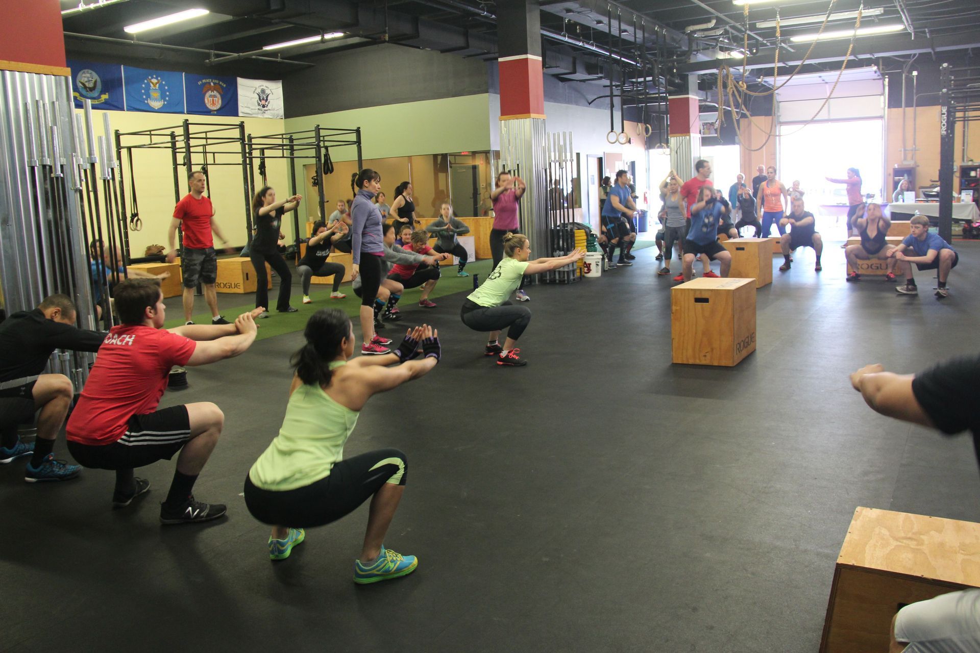 A group of people are squatting in a gym