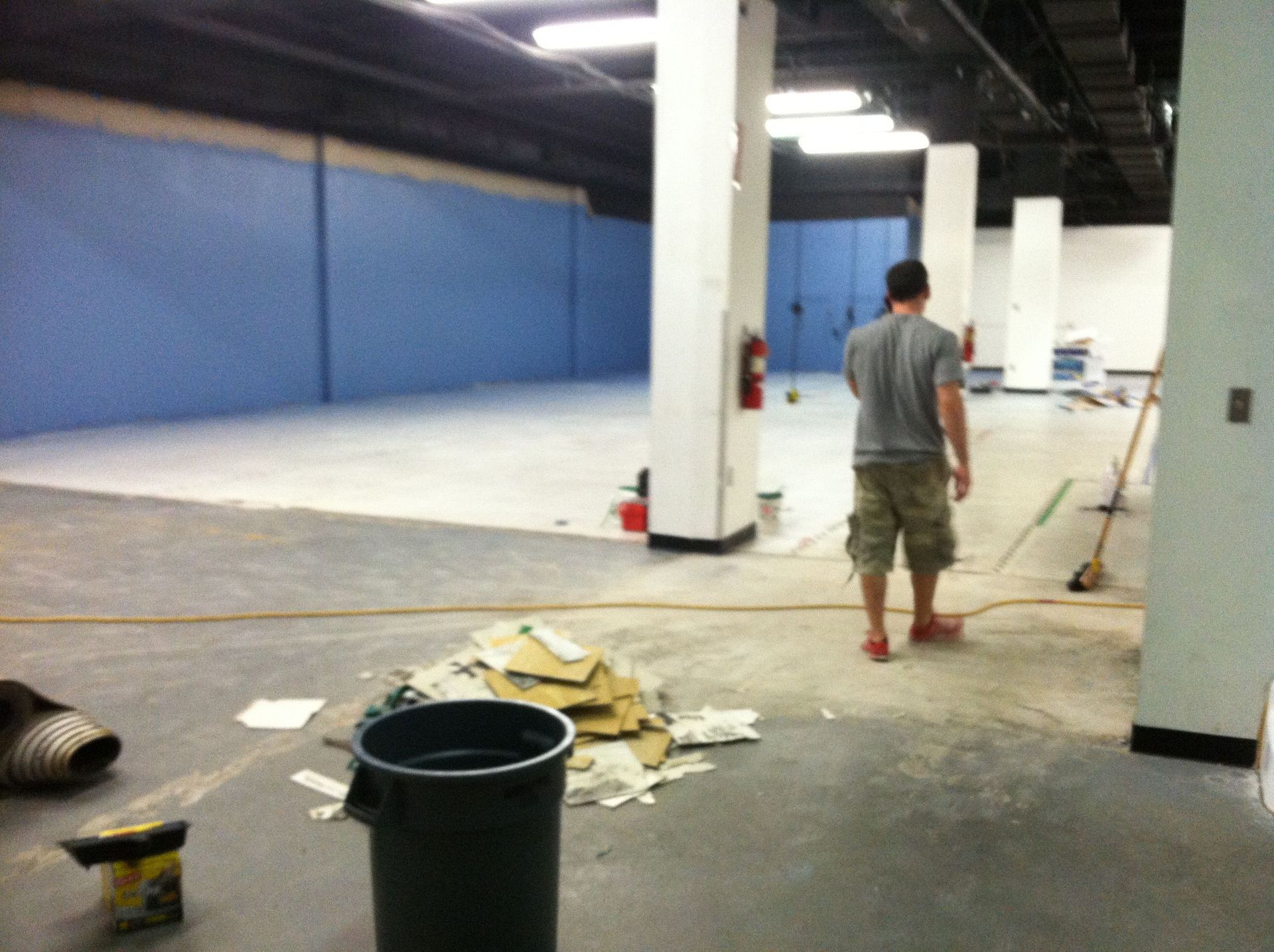 A man is standing in an empty room next to a trash can