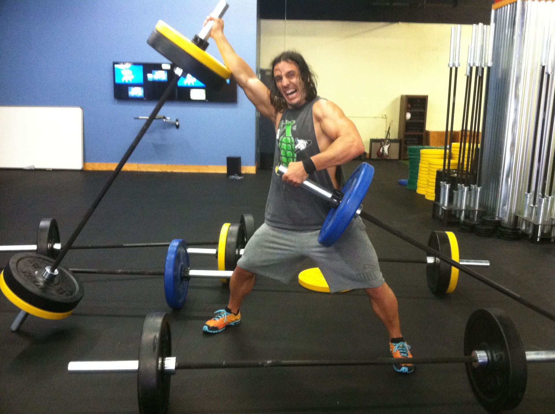 A man is holding a barbell in a gym