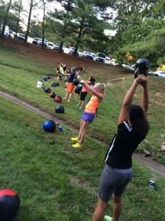 A group of people are doing exercises with kettlebells in a park