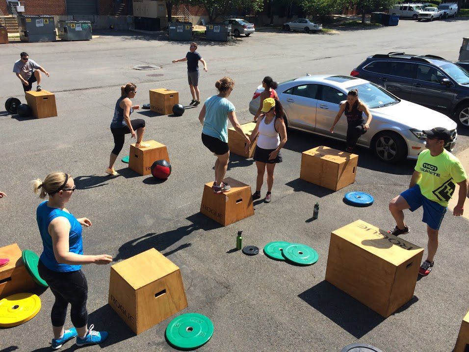 A group of people are doing exercises on boxes in a parking lot