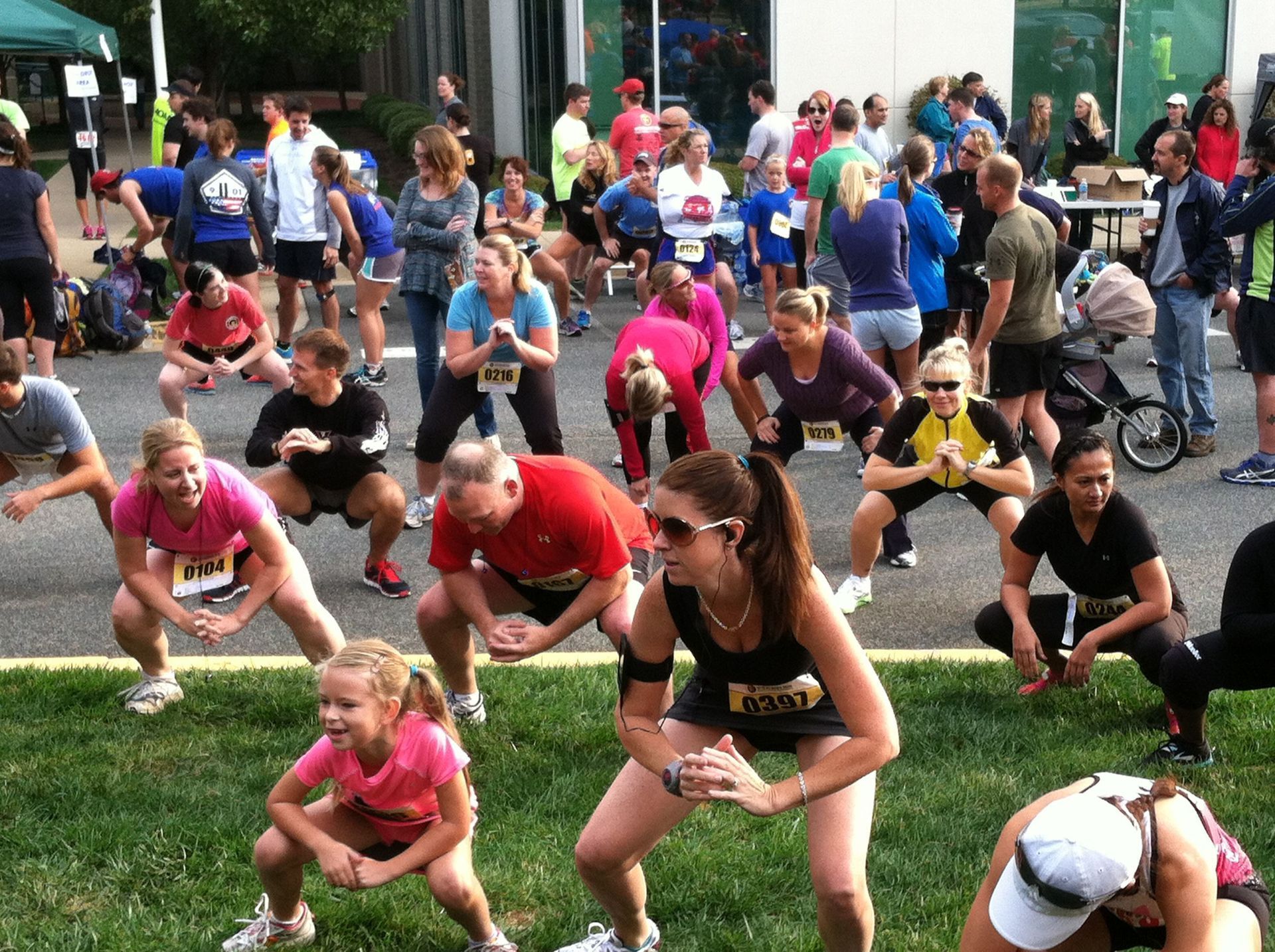 A group of people are doing stretching exercises and one of them has the number 1 on her shirt