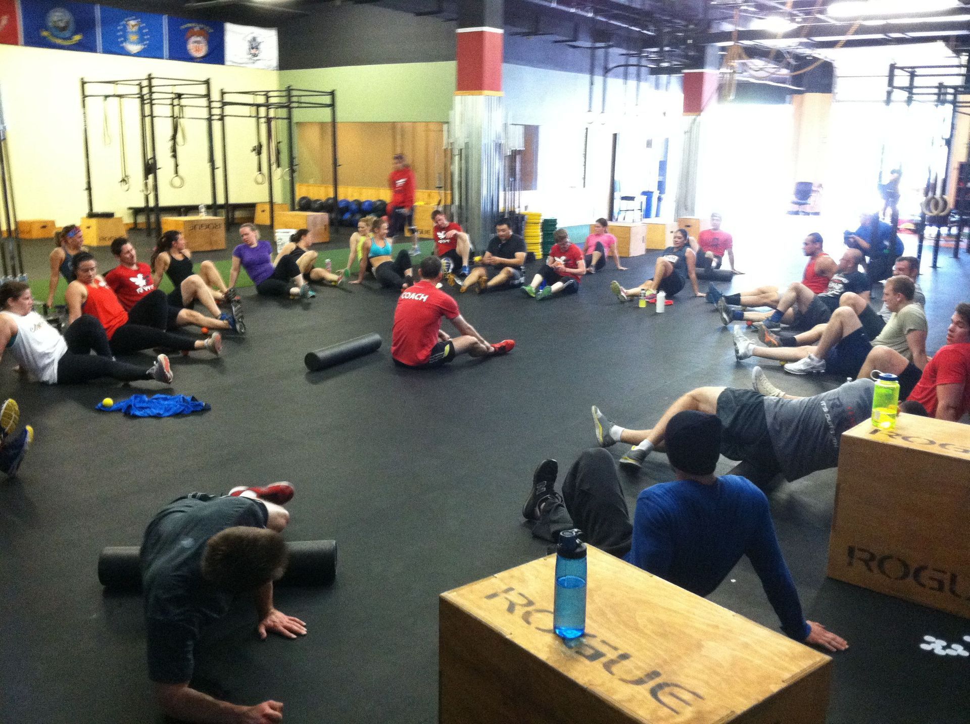 A group of people are doing exercises in a gym with a box that says rogue on it
