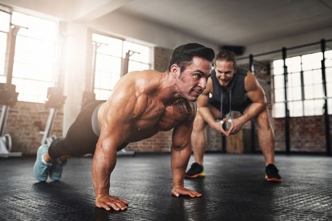 A man is doing push ups with a trainer in a gym