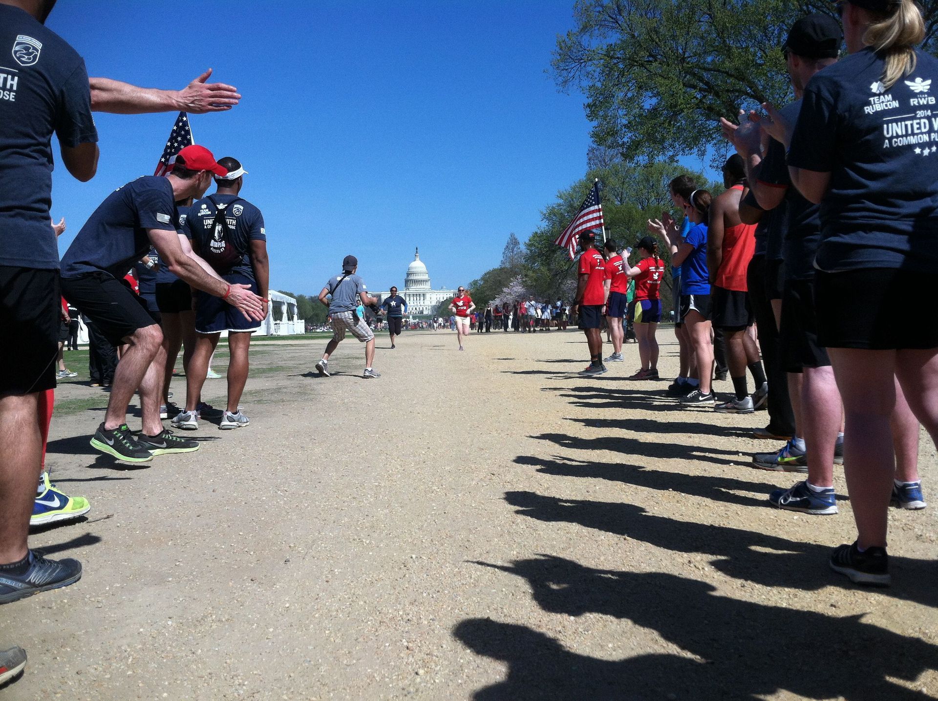 A group of people standing on a dirt road in front of the capitol building