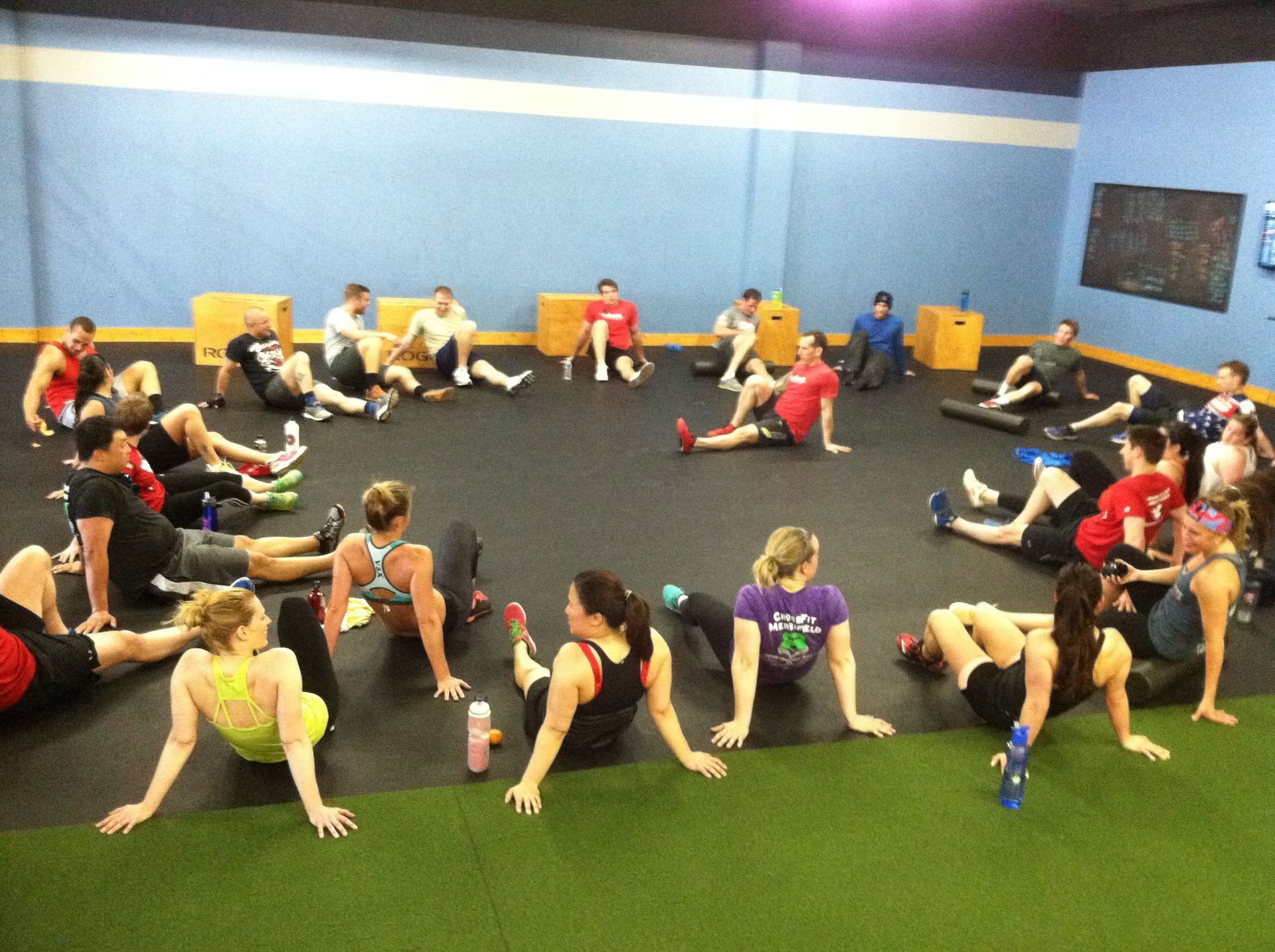 A group of people are doing stretching exercises in a gym