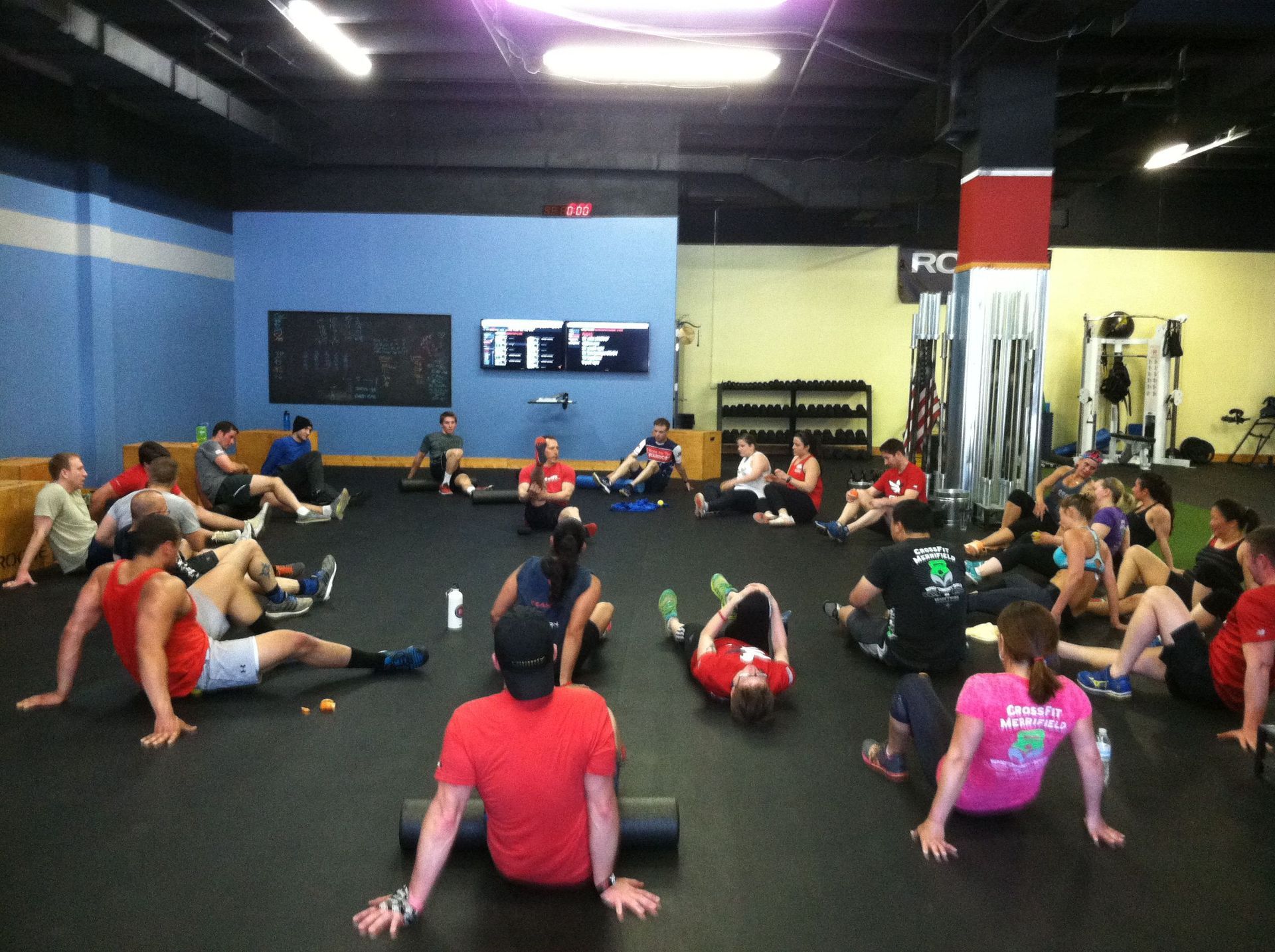 A group of people are sitting on the floor in a gym