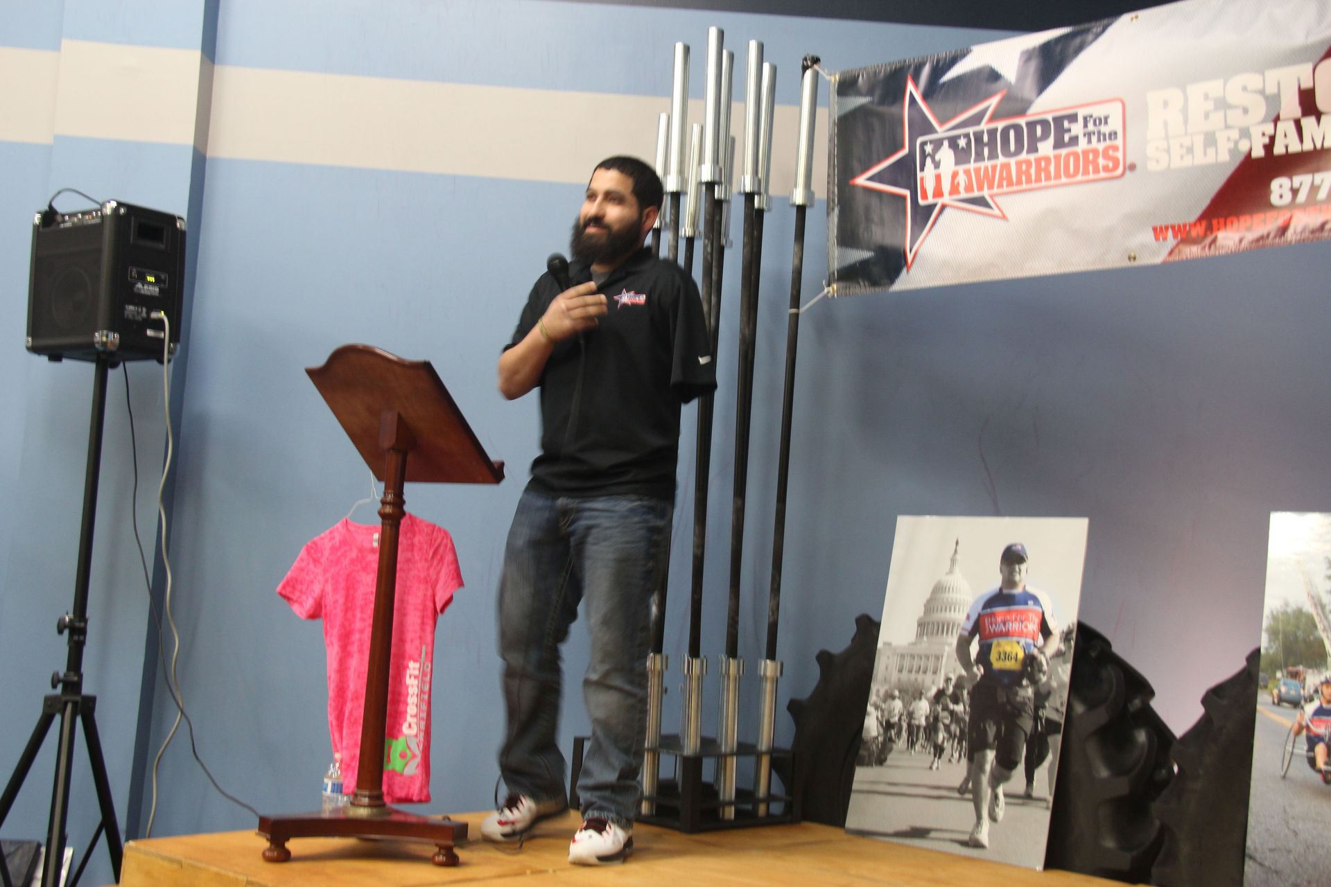 A man is giving a speech in front of a banner that says R shop