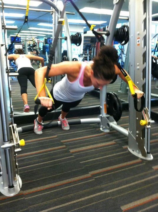 A woman is doing push ups on a machine in a gym