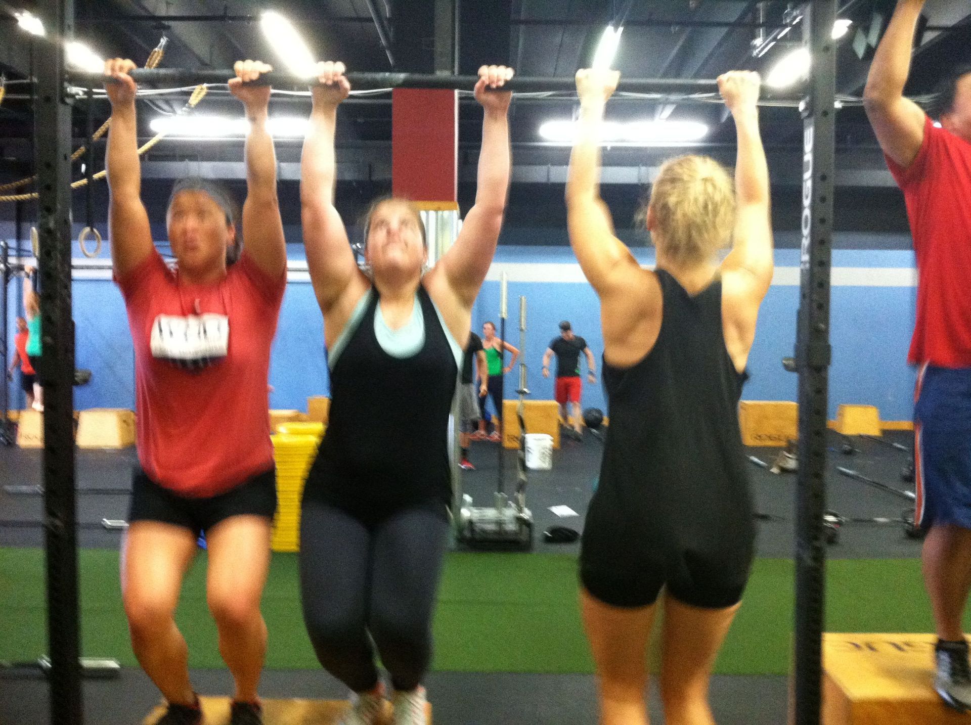 A group of people are doing pull ups in a gym