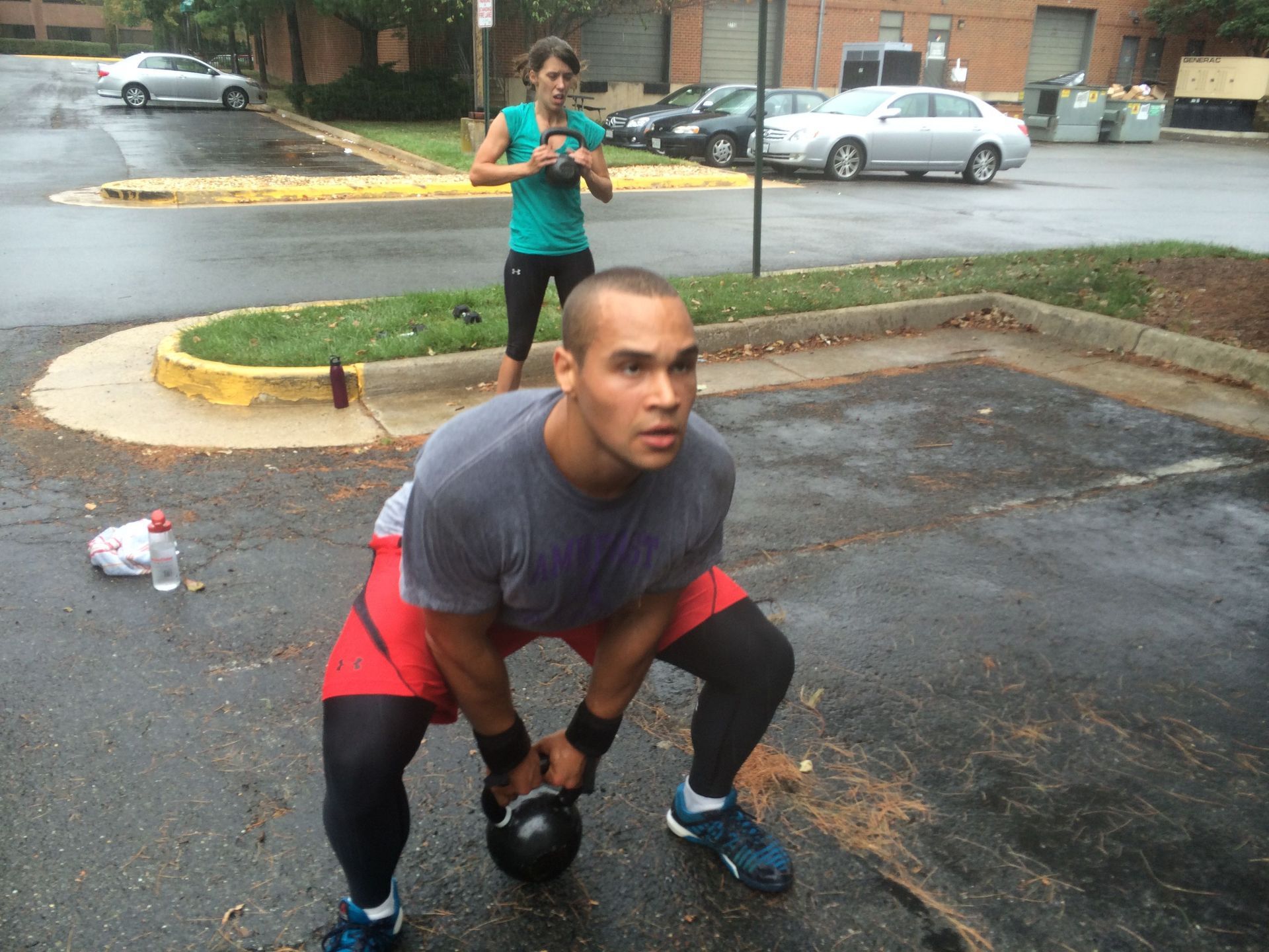 A man squatting down with a kettlebell in a parking lot