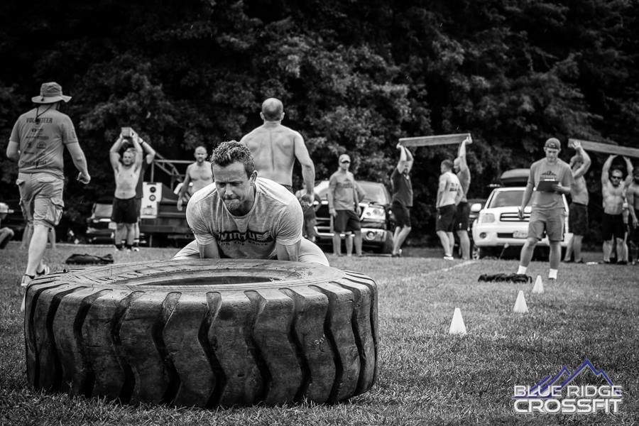 A man is crawling through a tire in a black and white photo