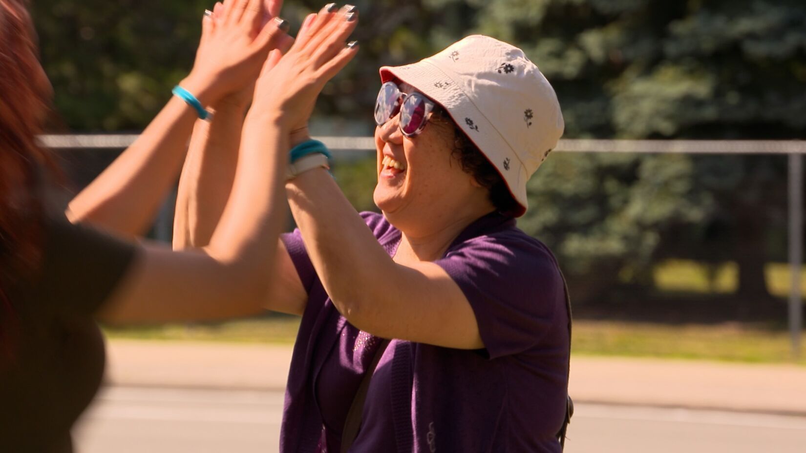 A woman in a white hat is giving a high five to another woman