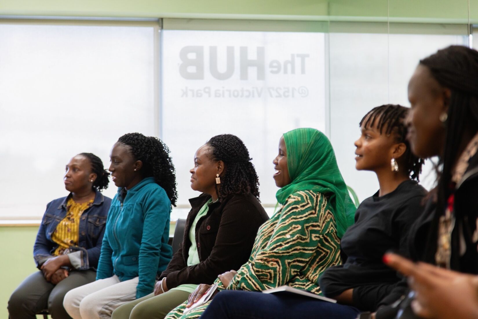 A group of women are sitting in a row in front of a projector screen.