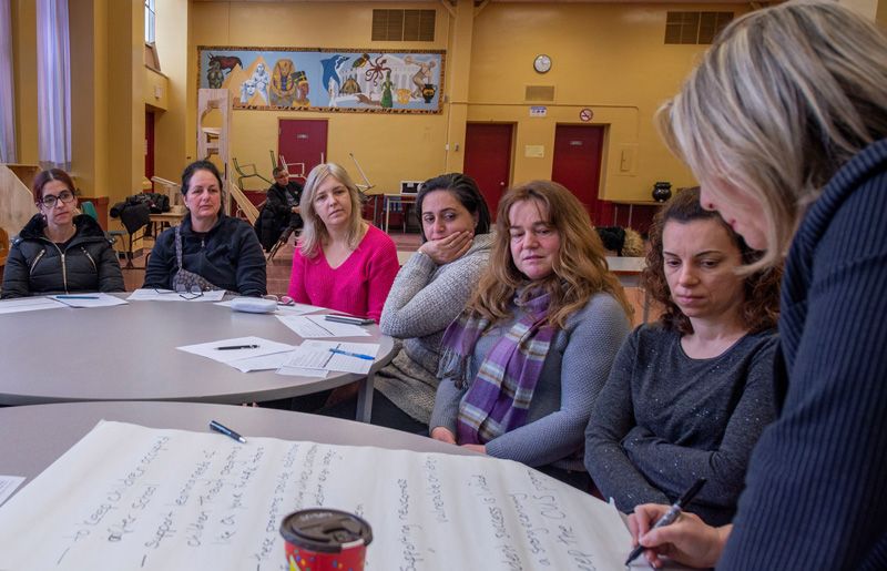 A group of women are sitting around a table in a room.