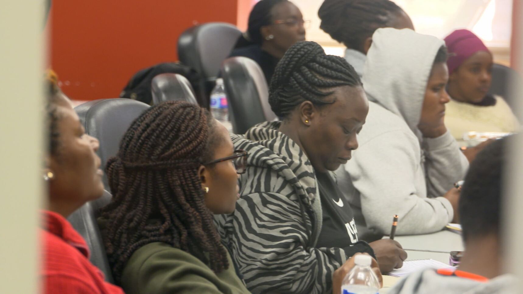 A group of people are sitting at a table with a bottle of water