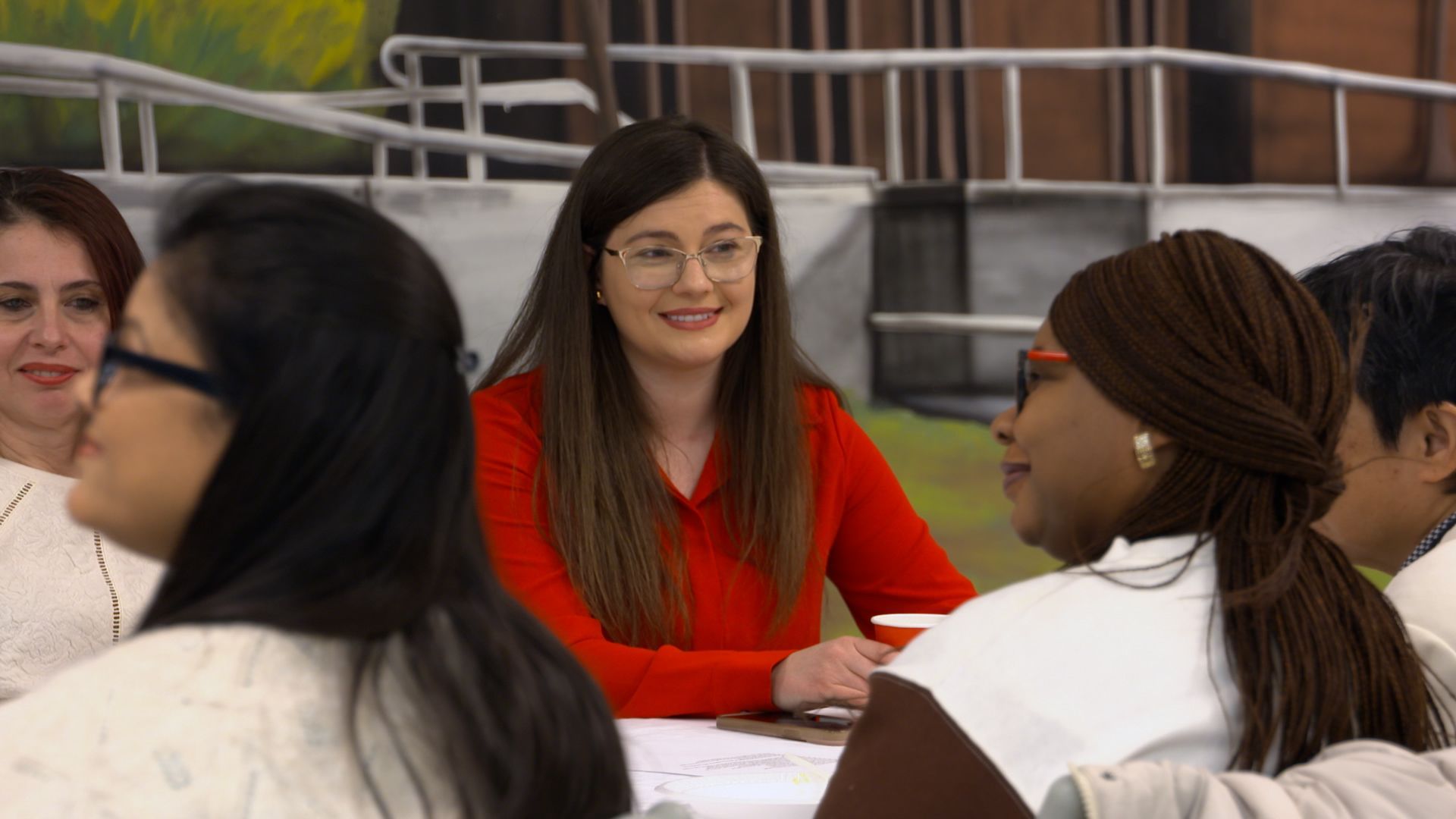 A group of people are sitting around a table talking to each other.