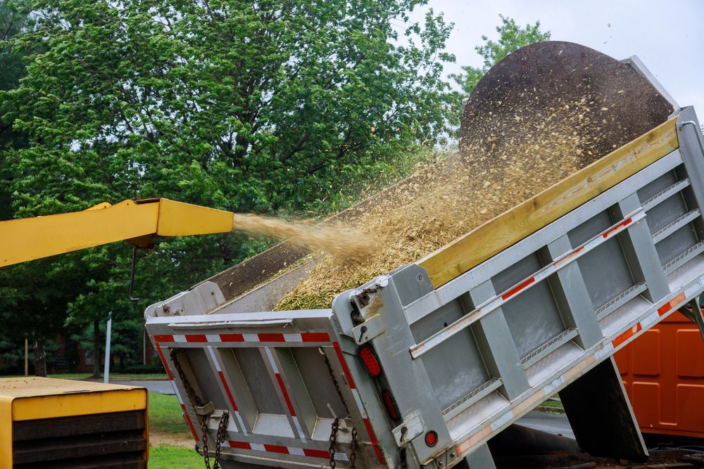 Wood Chips Being Blown From a Wood Chipper Into the Raised Bed — Heller Excavation & Tree Services in Ballina, NSW