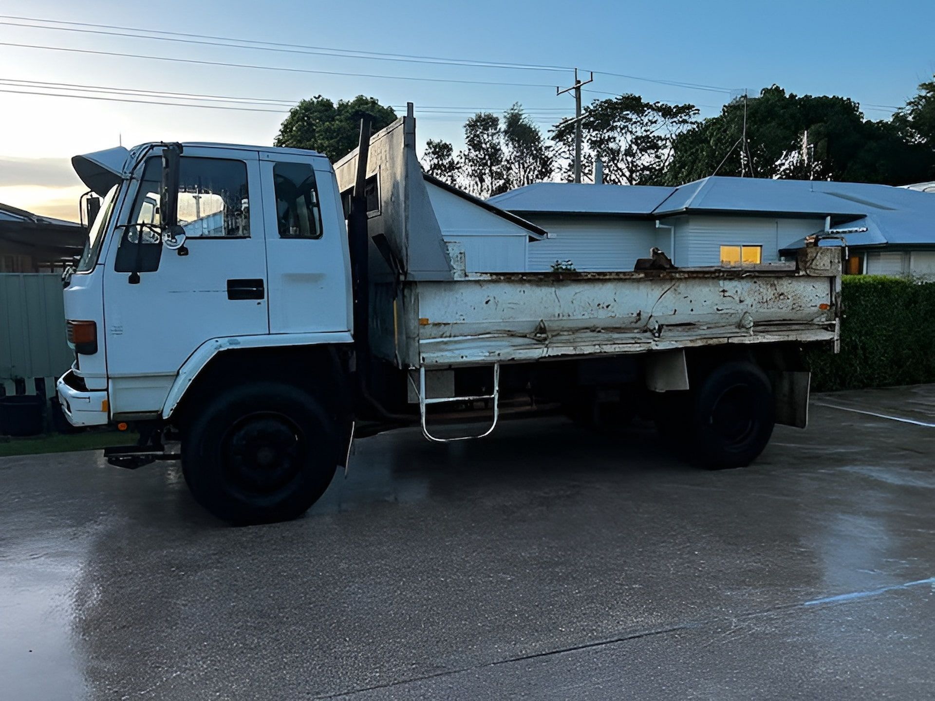 White Dump Truck Parked on A Wet Driveway a House — Heller Excavation & Tree Services in Mullumbimby, NSW