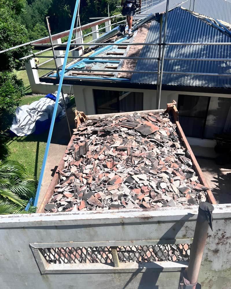 Roof Being Repaired; Rubble Pile, Worker on Roof — Heller Excavation & Tree Services in Mullumbimby, NSW