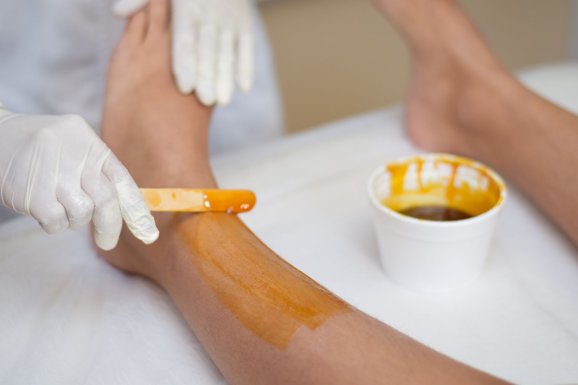 Uma mulher está depilando a perna em um salão de beleza.