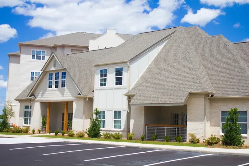 a large white apartment building is sitting on top of a grassy hill .