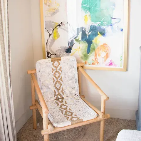 a chair is sitting in a corner next to a painting on the wall .