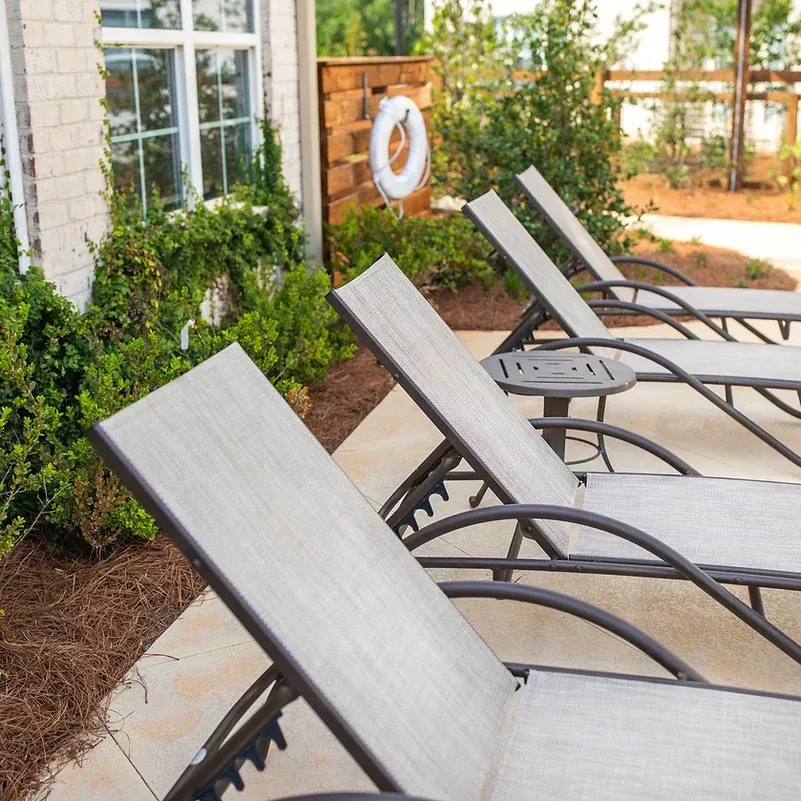 a row of lounge chairs are lined up in front of a house .