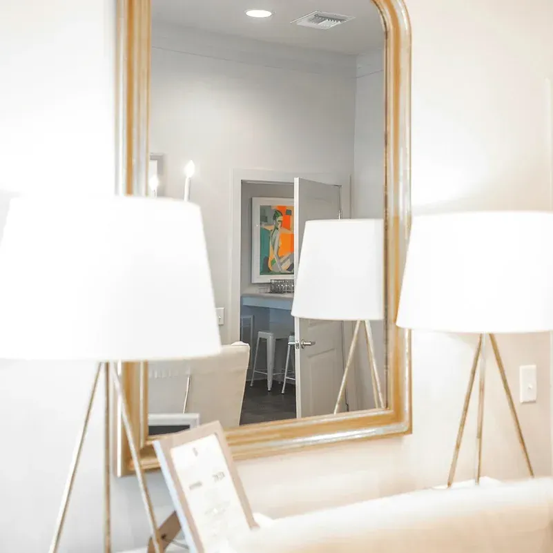 a living room with two lamps and a large mirror