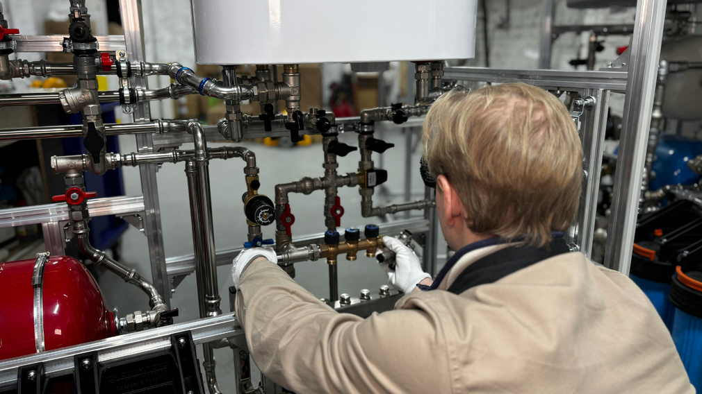 Person inspecting industrial pipes and valves in a factory setting