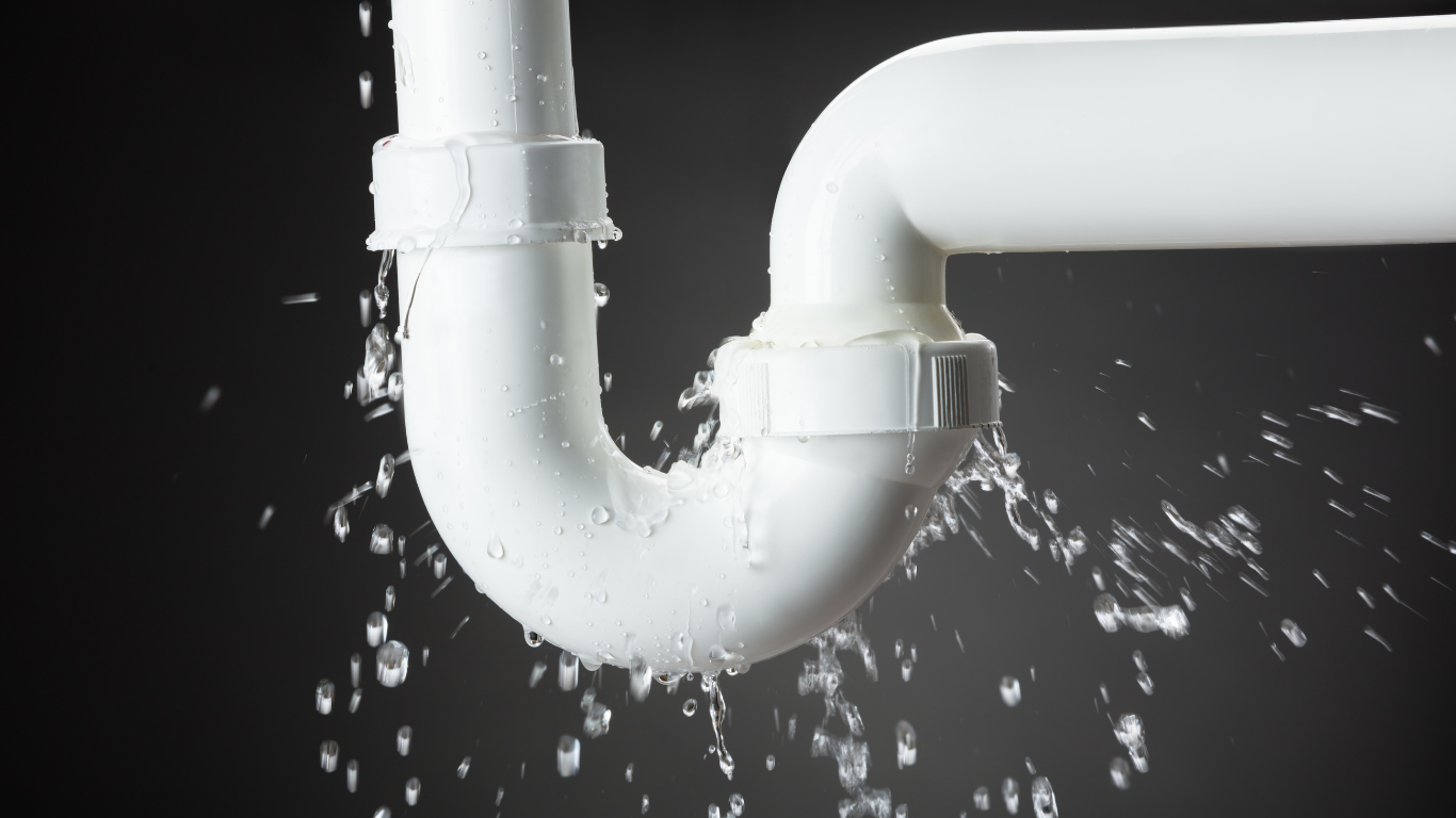 Leaky white plumbing pipes spraying water on a dark background