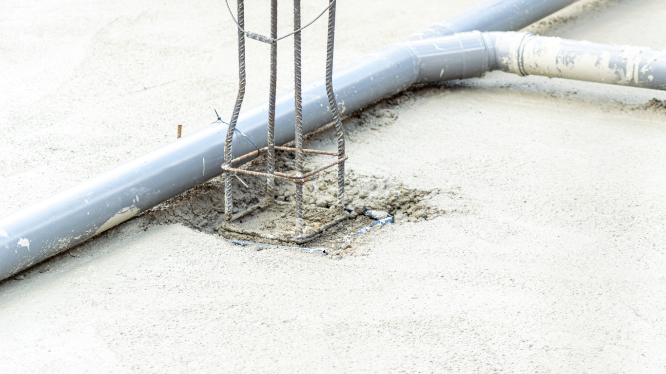 Damaged concrete around exposed rebar and a bent pipe on a white floor