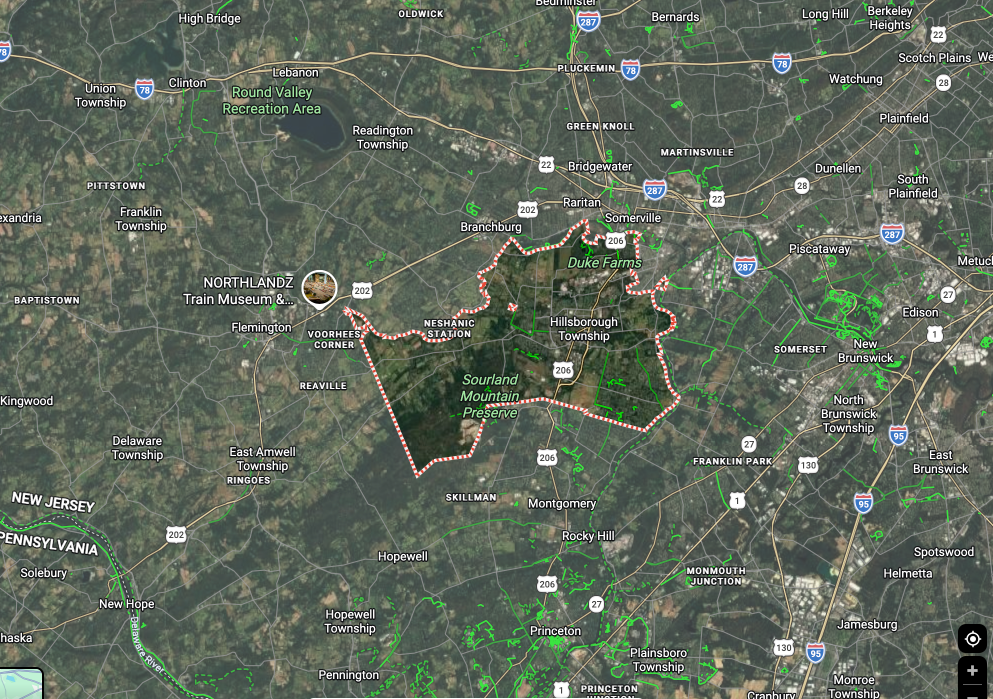 Satellite map showing a highlighted city boundary in pink over green rural terrain with roads and labels