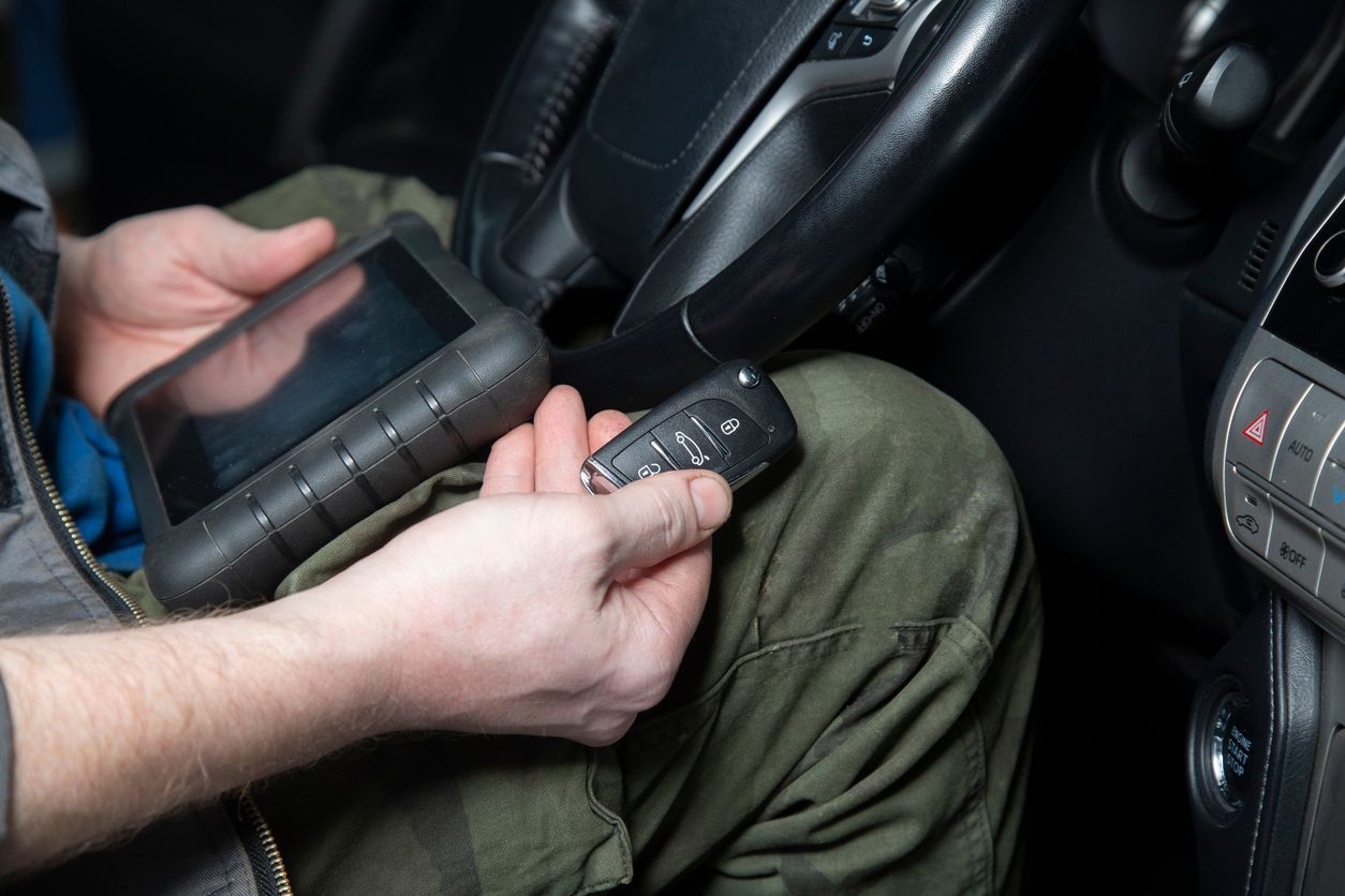 Person holding a car key and a diagnostic tool inside a vehicle.
