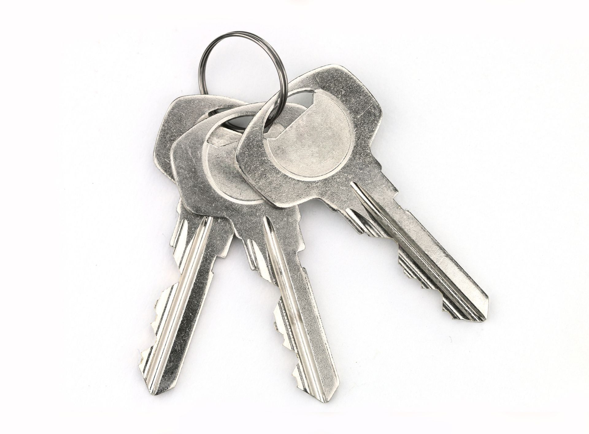 Three silver keys on a ring, resting on a white surface.