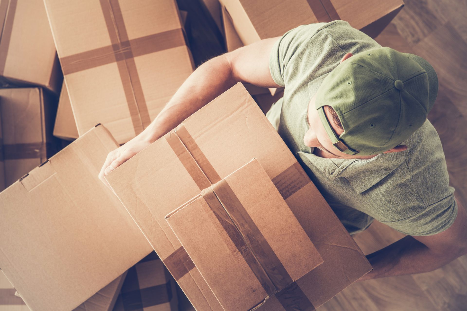 A man carefully carries a moving box, maintaining a sturdy grip as he navigates through a space.