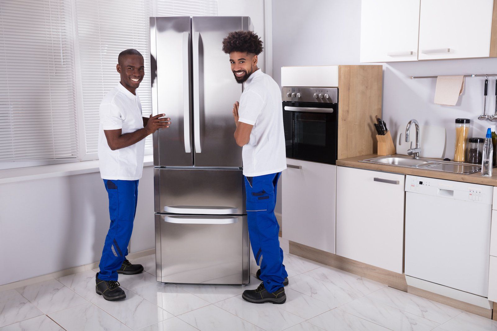 Two men in work attire diligently repairing the kitchen freezer.