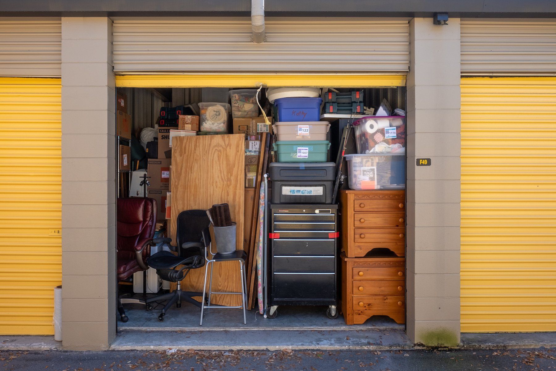 Open storage unit door reveals a neatly organized collection of furniture, boxes, and belongings from a house.