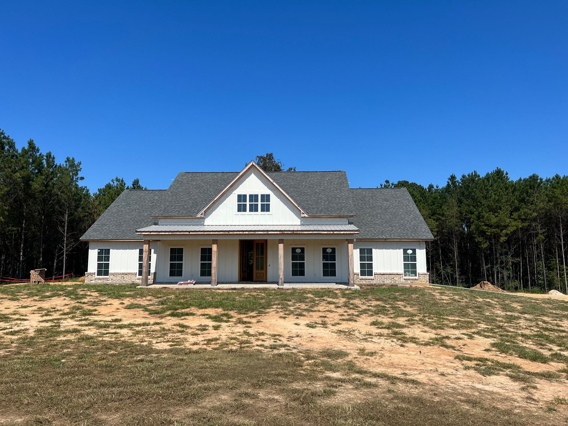 New construction white farmhouse with brick border painted by Covington Painter in Covington, Louisiana